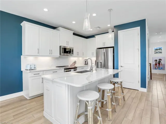 Kitchen featuring stainless steel appliances, wood finish floors, a sink, visible vents, and tasteful backsplash