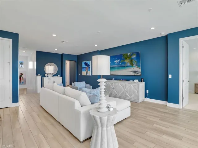 Living room with light wood-type flooring, baseboards, visible vents, and recessed lighting