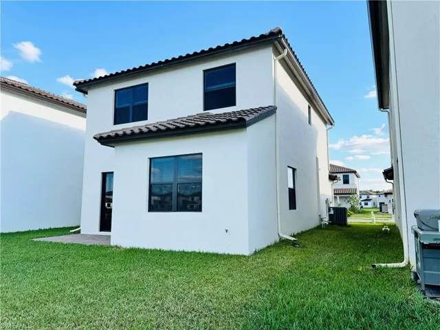 Rear view of house featuring a yard and cooling unit