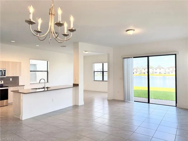 Kitchen featuring light brown cabinets, an inviting chandelier, a water view, sink, and appliances with stainless steel finishes
