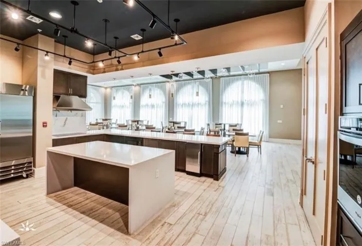 Kitchen featuring a healthy amount of sunlight, light hardwood / wood-style floors, a spacious island, dark brown cabinets, and appliances with stainless steel finishes