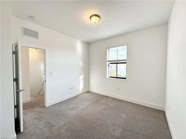 Carpeted empty room with a textured ceiling
