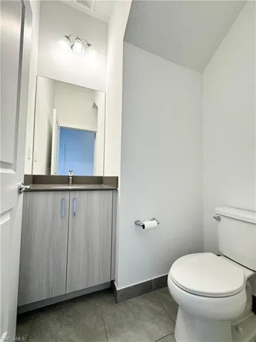 Bathroom with tile patterned flooring, vanity, a textured ceiling, and toilet