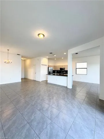 Unfurnished living room with tile patterned floors, a textured ceiling, and a notable chandelier