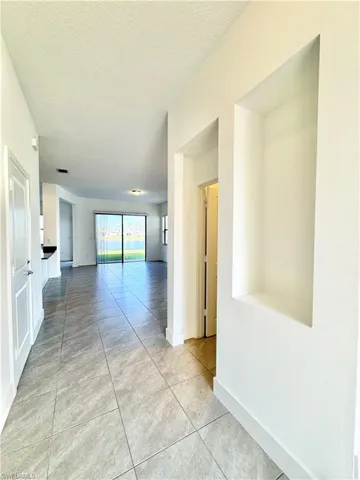 Hallway featuring light tile patterned floors and a textured ceiling