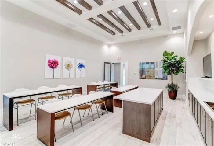 Kitchen with beamed ceiling, a towering ceiling, a center island, and light hardwood / wood-style floors