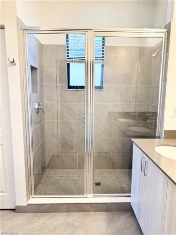 Bathroom featuring tile patterned flooring, vanity, and an enclosed shower