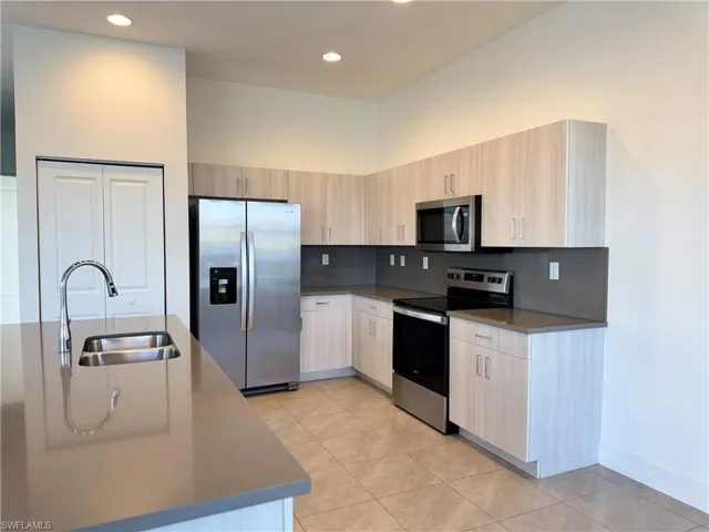 Kitchen featuring sink, light tile patterned floors, stainless steel appliances, and light brown cabinets