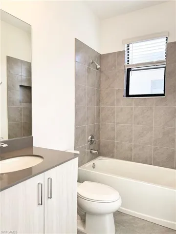 Full bathroom featuring toilet, tile patterned flooring, vanity, and tiled shower / bath