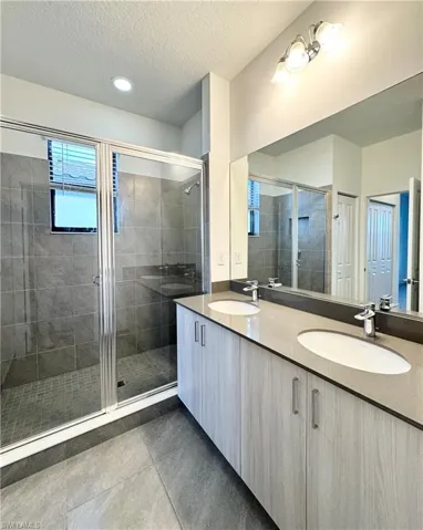 Bathroom featuring tile patterned flooring, vanity, a textured ceiling, and walk in shower