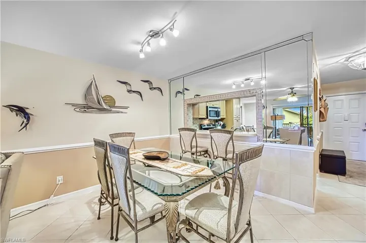 Dining area featuring mirrored walls, a track lighting fixture, and tiled flooring