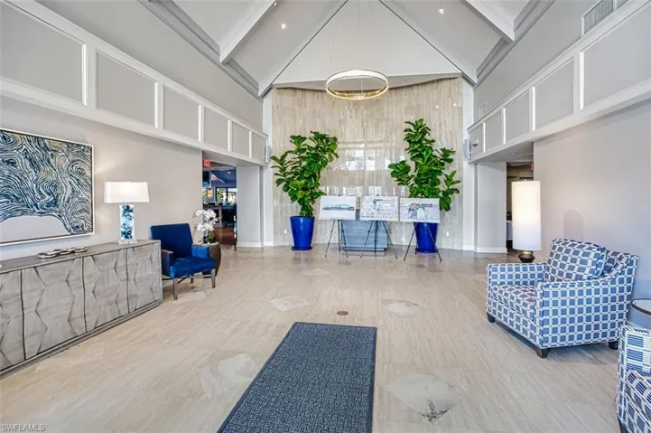 Vaulted ceilings with architectural detailing, natural stone wall accent, large format tile flooring, and integrated overhead lighting