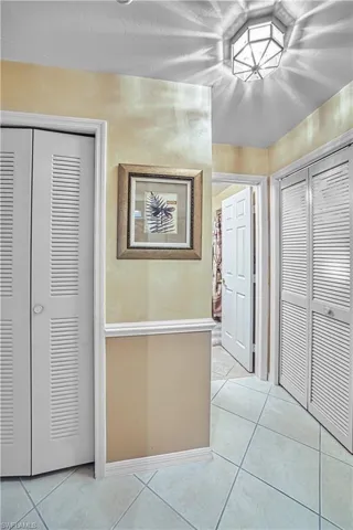 Tiled flooring with geometric patterns, interior doors with louvered panels, decorative wall trim, and a ceiling-mounted light fixture