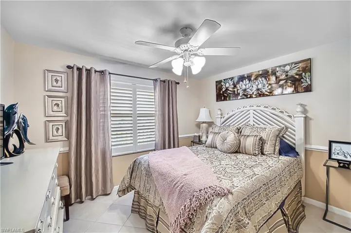 Ceiling fan with integrated lighting, window with white plantation shutters, tile flooring, and wall molding