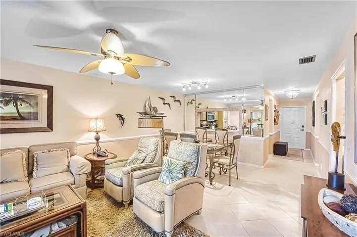 Ceiling fan with integrated lighting, wall-mounted mirror panels, recessed lighting, tile flooring, and a paneled entry door