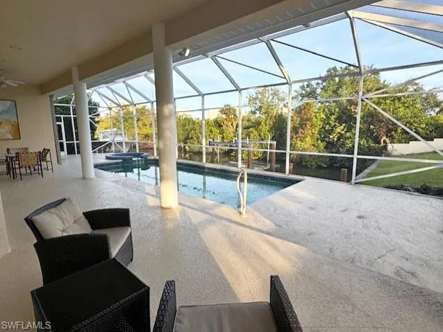 View of pool with glass enclosure, a patio area, and an in ground hot tub