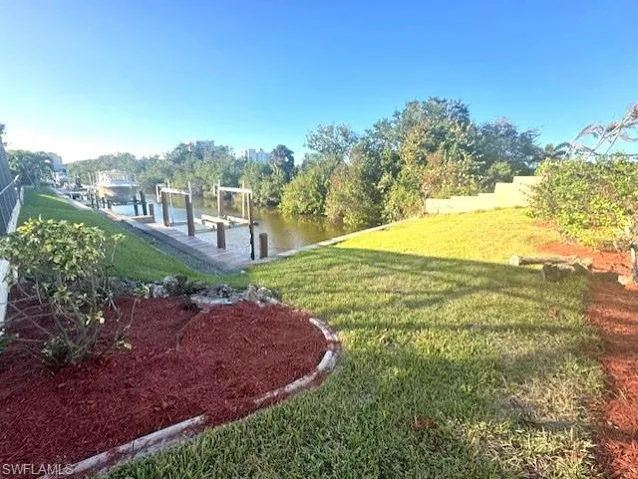 View of yard with a water view and a dock