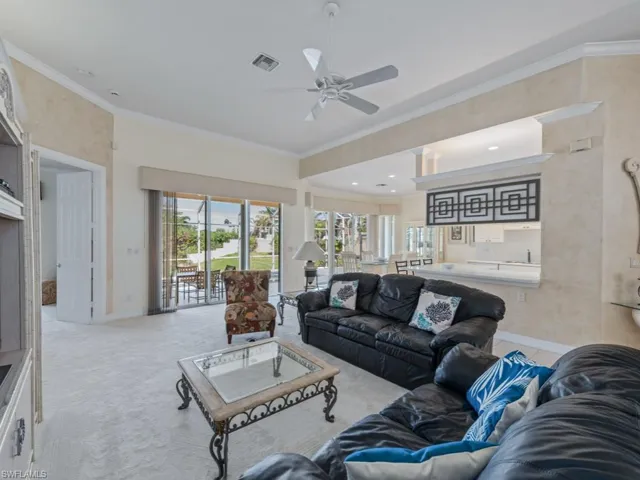 Living room featuring crown molding, ceiling fan, and light colored carpet