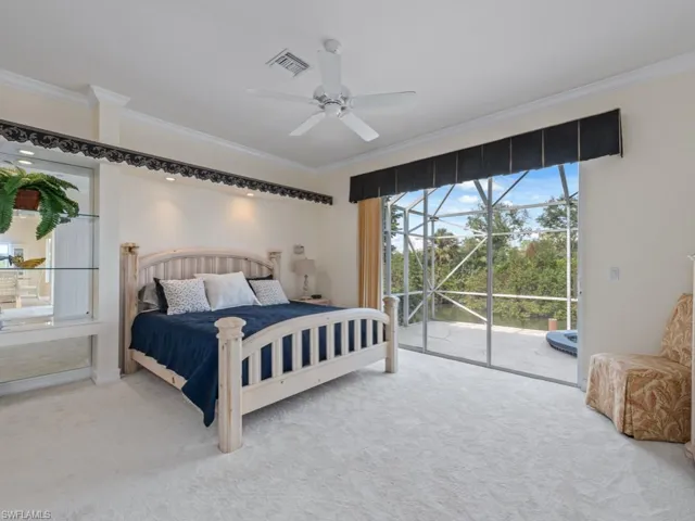 Carpeted bedroom with ceiling fan, access to exterior, and crown molding