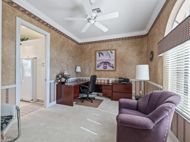 Carpeted office with ceiling fan and crown molding