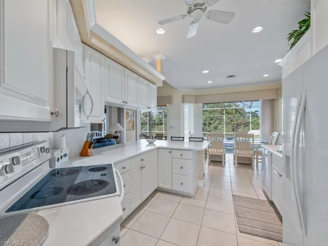Kitchen featuring kitchen peninsula, white appliances, white cabinetry, and a healthy amount of sunlight