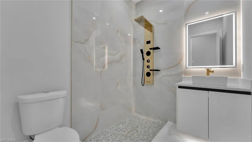 Bathroom featuring tiled shower, vanity, and toilet