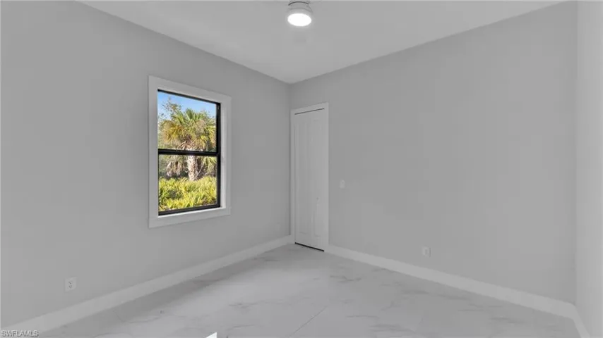 Unfurnished room with marble finish floor, a ceiling fan, and baseboards