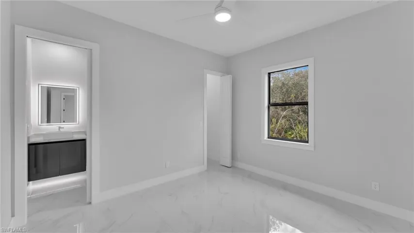 Unfurnished bedroom featuring ceiling fan, sink, and ensuite bathroom