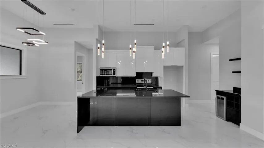 Kitchen featuring white cabinetry, sink, backsplash, beverage cooler, and pendant lighting