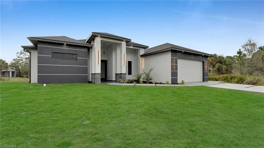 View of front facade featuring a garage and a front lawn