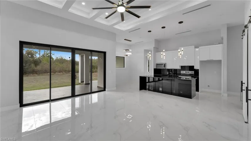 Kitchen with stainless steel appliances, a towering ceiling, pendant lighting, a center island, and white cabinetry