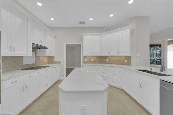 Kitchen with a sink, under cabinet range hood, dishwasher, a kitchen island, and recessed lighting