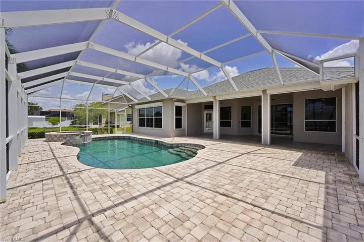 View of pool featuring a pool with connected hot tub, a patio, and glass enclosure