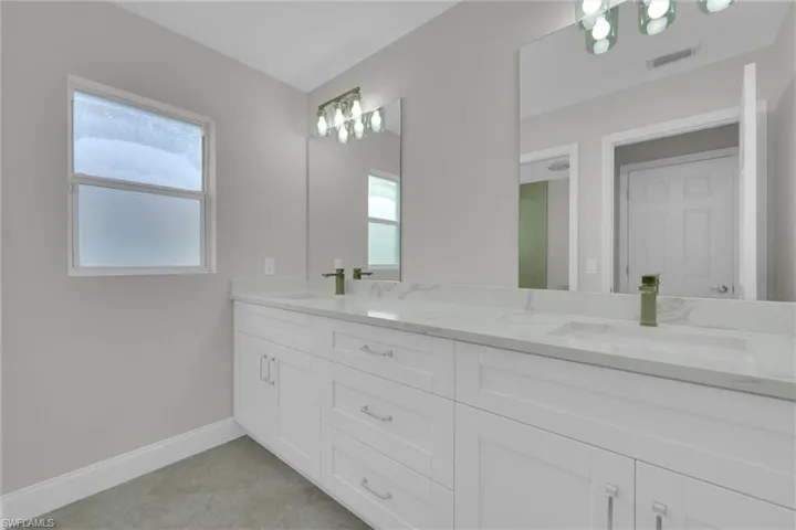 Full bathroom with a sink, double vanity, baseboards, and visible vents