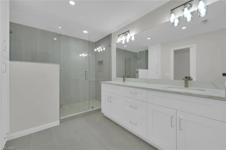 Full bathroom featuring tile patterned floors, visible vents, a shower stall, and a sink