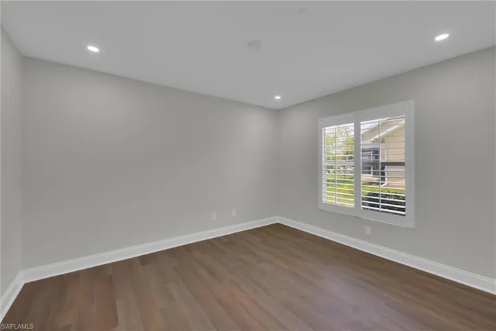 Empty room with dark wood-style flooring, baseboards, and recessed lighting