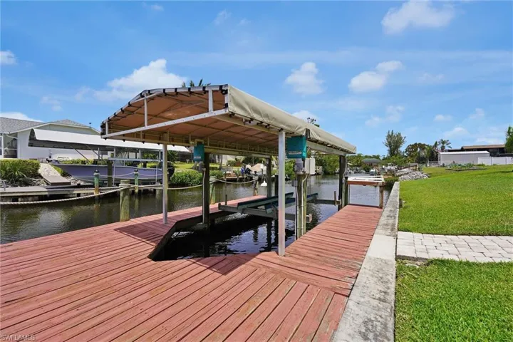 Dock area featuring a water view, boat lift, and a lawn