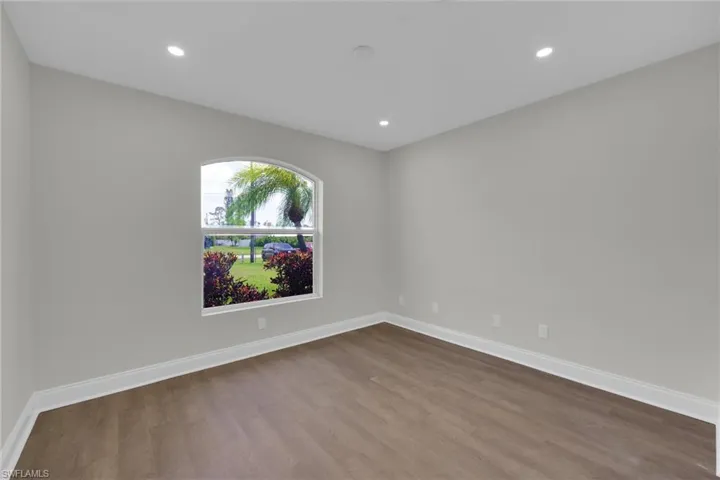Empty room with dark wood-type flooring, baseboards, and recessed lighting