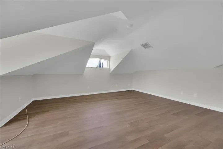 Additional living space featuring baseboards, vaulted ceiling, wood finished floors, and visible vents