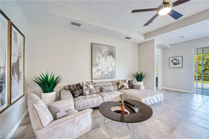Living room featuring a raised ceiling and ceiling fan