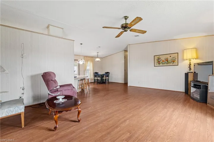 Living area featuring light wood-style flooring, ceiling fan, a textured ceiling, and a chandelier