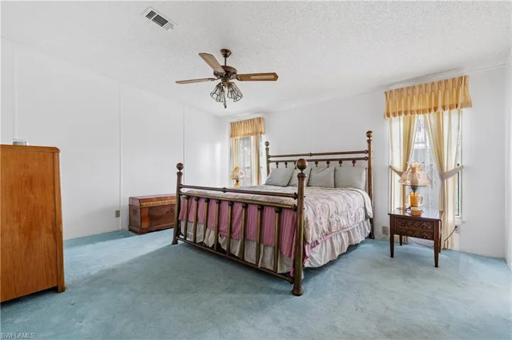 Carpeted bedroom with a ceiling fan and a textured ceiling