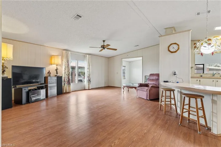 Living room featuring light wood finished floors, a textured ceiling, and ceiling fan