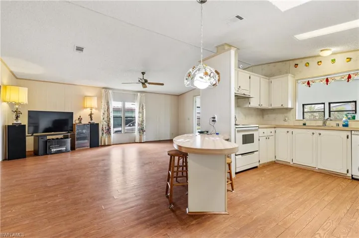 Kitchen with open floor plan, healthy amount of natural light, light countertops, hanging light fixtures, and a textured ceiling