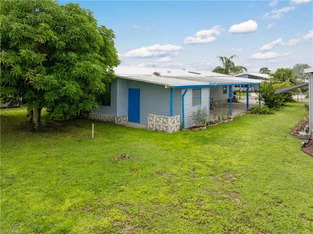 Back of property featuring a metal roof, a yard, a patio area, and a carport