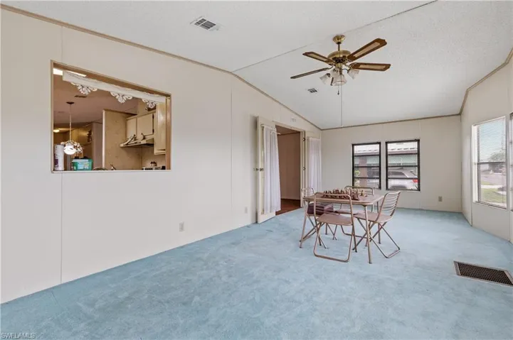 Dining area featuring carpet flooring, a ceiling fan, vaulted ceiling, a textured ceiling, and crown molding
