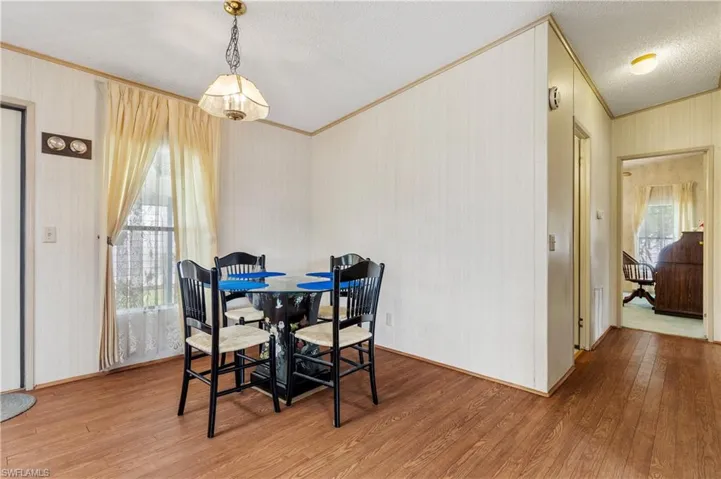 Dining area featuring light wood-style floors, plenty of natural light, crown molding, and a textured ceiling