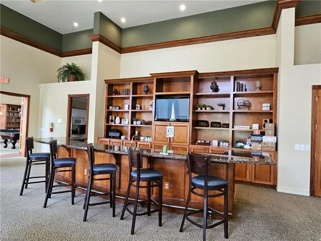 Bar with carpet floors, dark stone counters, pool table, and a towering ceiling