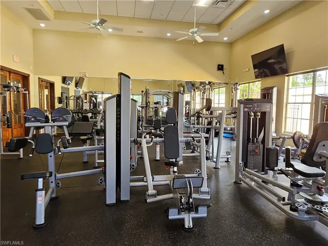 Exercise room featuring a drop ceiling, a towering ceiling, ceiling fan, and plenty of natural light