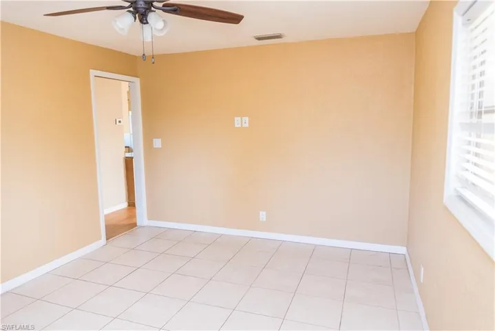 Empty room with plenty of natural light, a ceiling fan, and light tile patterned flooring